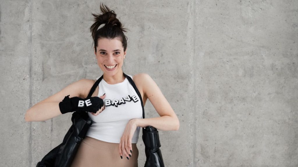 Confident woman posing with boxing gloves and 'Be Brave' message.