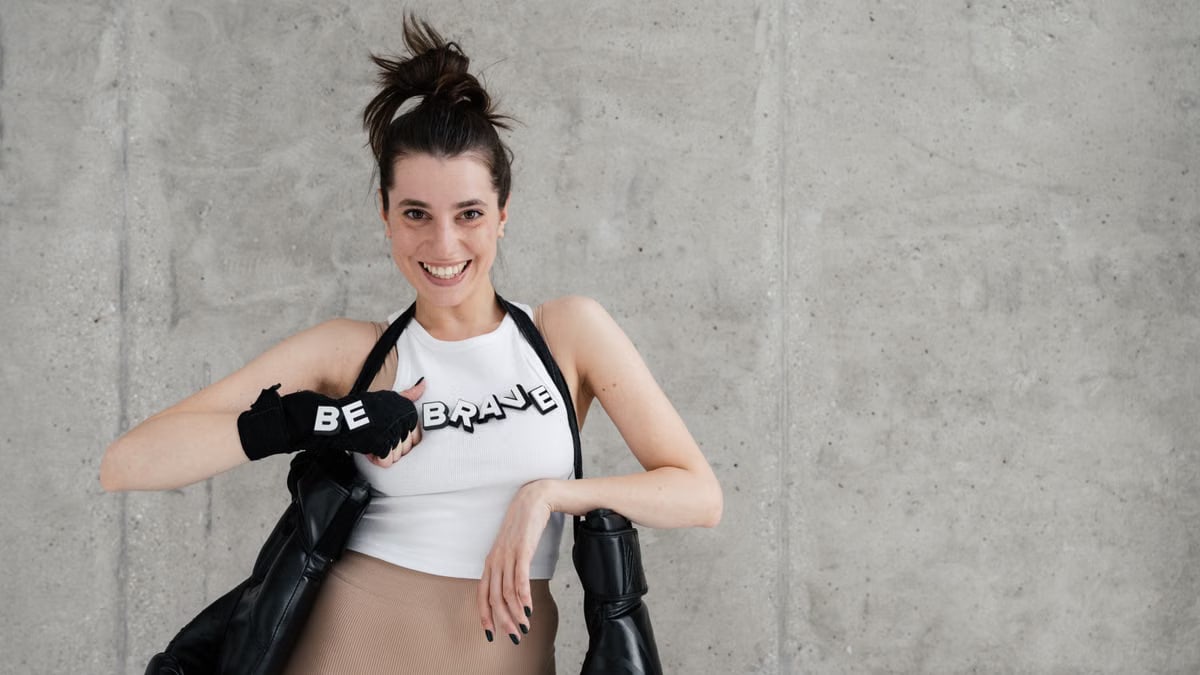 Confident woman posing with boxing gloves and 'Be Brave' message.